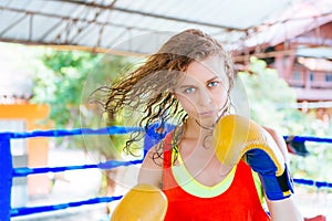 Female boxer inside thai boxing ring. angree emotions.