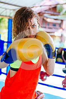 Female boxer inside thai boxing ring. angree emotions.