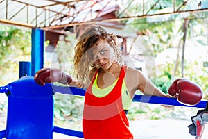 Female boxer inside thai boxing ring. angree emotions.