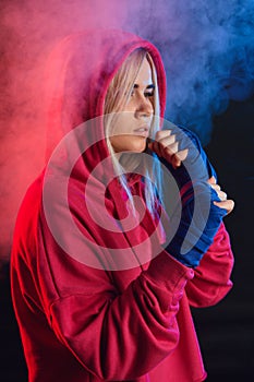 Female boxer prepares to punch at a boxing studio. Woman boxer in motion