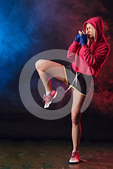 Female boxer prepares to punch at a boxing studio. Woman boxer in motion
