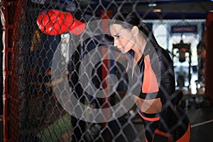 Female boxer standing inside a boxing cage.