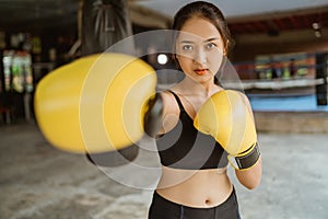 a female boxer with yellow boxing gloves standing with punching moves