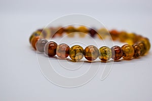 The female bracelet, made of small amber stones, rests on a white background