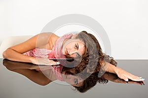 Female brunette leaning on glass table with reflection