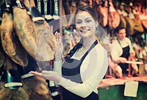 Female brunette selling jamon in delicatessen store