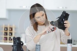 Female with brush cleaning black leather shoe