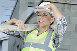 female builder carrying wood on site