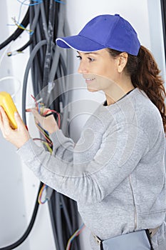female builder checking wiring installation with multimeter