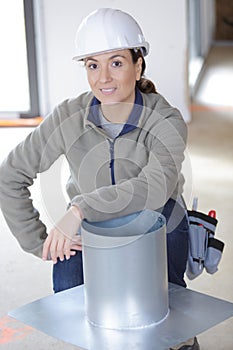 Female builder crouched by metal chimney flue