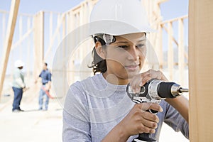 A female builder drilling