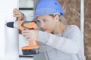 female builder drilling wall