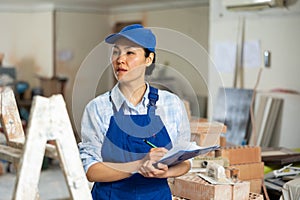 Female builder fills out documentation during repair work