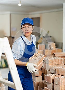 Female builder is laying bricks on top of each other