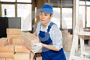 Female builder is laying bricks on top of each other