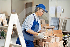 Female builder is laying bricks on top of each other