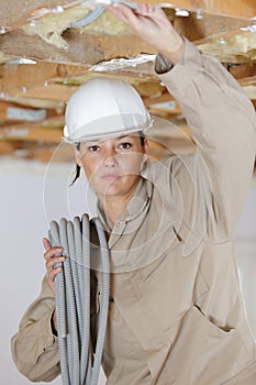 Female builder with roll grey corrugated tubing on shoulder