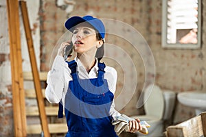 Female builder talking on phone with owner of building under renovation