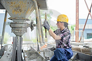 female builder using cement mixer on building site