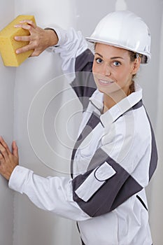 Female builder using sponge on wall