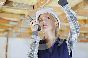 Female builder using walkie talkie on renovation site