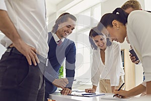 Female business consultant helping young team of happy workers outlining key points of work