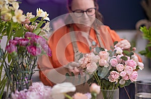 female business owner arranges a beautiful bouquet of colorful flowers, interior floral shop.