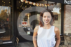 Female business owner standing in the street outside cafe