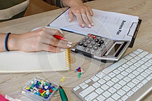 Female with Business plan, calculator and pen on the table. Woman working in office, sitting at desk, using computer
