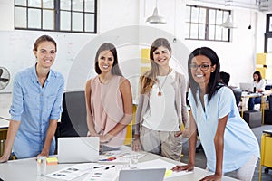Female business team stand at office desk looking to camera