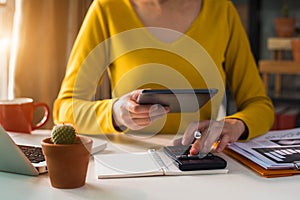 Female businessman working on desk office with using a calculator to calculate.