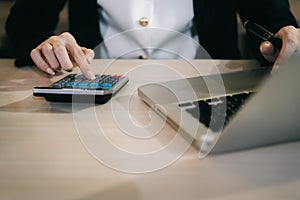 Female businessman working on desk office with using a calculator to calculate the numbers, finance accounting concept