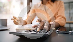 Female businessman working on desk office with using a calculator to calculate the numbers, finance accounting concept