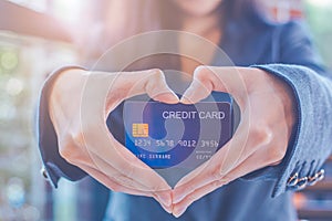 Female businessmen are holding a credit card and making a heart-shaped hand