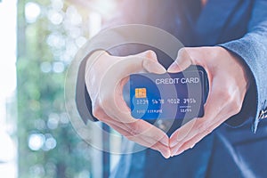 Female businessmen are holding a credit card and making a heart-shaped hand