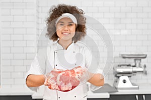 Female butcher demonstrating meat in supermarket.