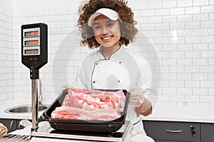 Female butcher demonstrating meat in supermarket.