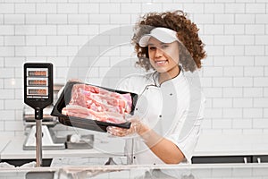 Female butcher demonstrating meat in supermarket.