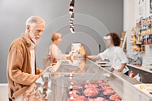 Female butcher giving sausages to woman.