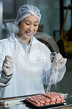 Female butcher packing raw sausages