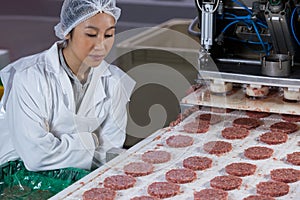 Female butcher processing hamburger patty