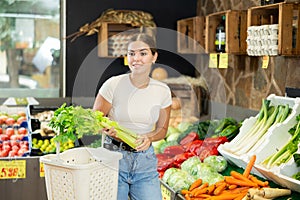 Female buyer chooses celery and fresh vegetables in food store