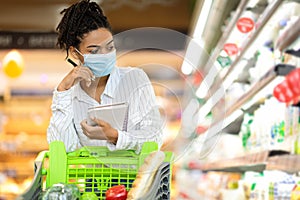 Female Buyer Doing Grocery Shopping Calculating Food Prices In Supermarket