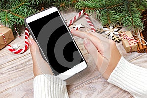 Female buyer makes order at screen of smartphone with copy space. Winter holidays sales. Christmas online shopping