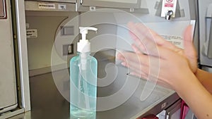 Female cabin crew hand washing with alcohol gel in aircraft galley.