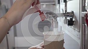 Female cabin crew pouring hot water into paper cup covered with cup sleeve in aircraft aft galley.