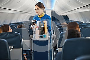 Female cabin crew showing package with coffee to woman traveller