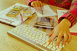 Female with calculator, pen, notes and banknotes on a wooden table