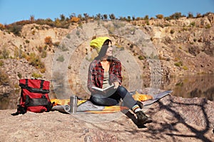 Female camper reading book while sitting on sleeping bag