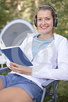 female camper reading book while sitting in wilderness